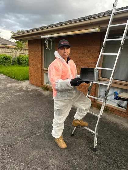 Technician holding a steel possum one way door next to his ladder