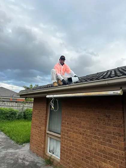 Technician on a tiled roof beside a one way door he has just fitted